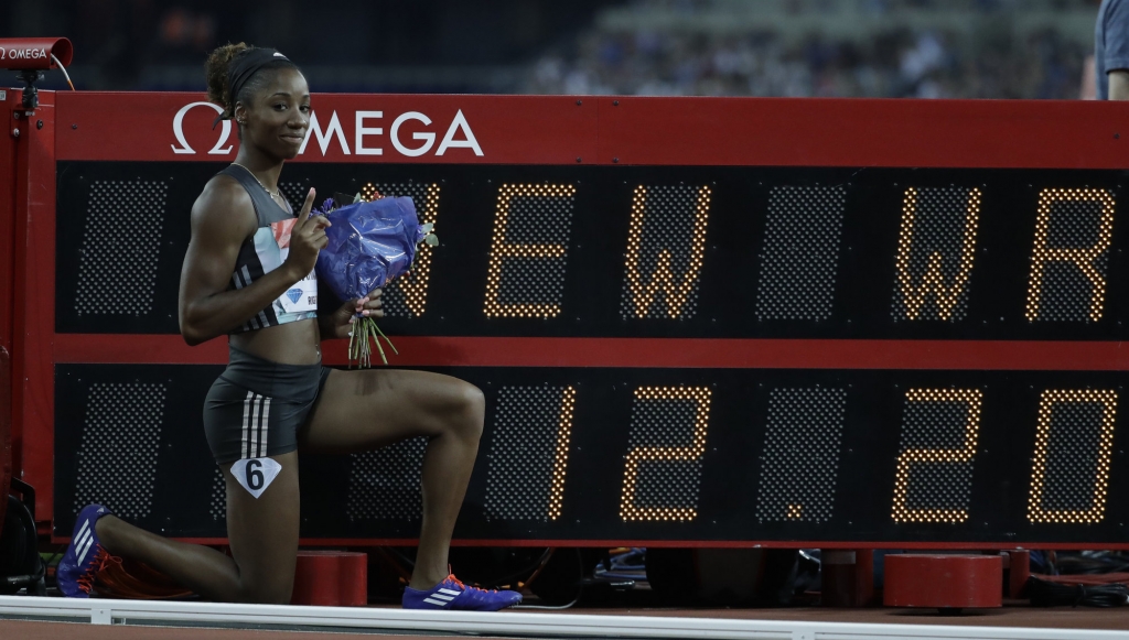 Kendra Harrison of the US poses next to the time she ran to win the women's 100 meter hurdles in a world record time of 12.20 seconds during the Diamond League anniversary games at The Stadium in the Queen Elizabeth Olympic Park in London Friday J