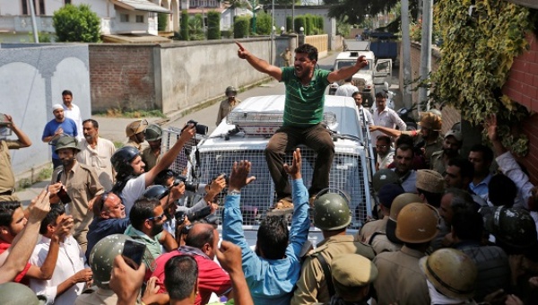 A supporter of Mirwaiz Umar Farooq a separatist political leader shouts slogans atop a police vehicle during a protest in Srinagar against the recent killings in Kashmir