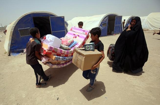 Iraqis displaced from the city of Fallujah collect aid distributed by the Norwegian Refugee Council at a newly opened camp in Amriyat al Fallujah