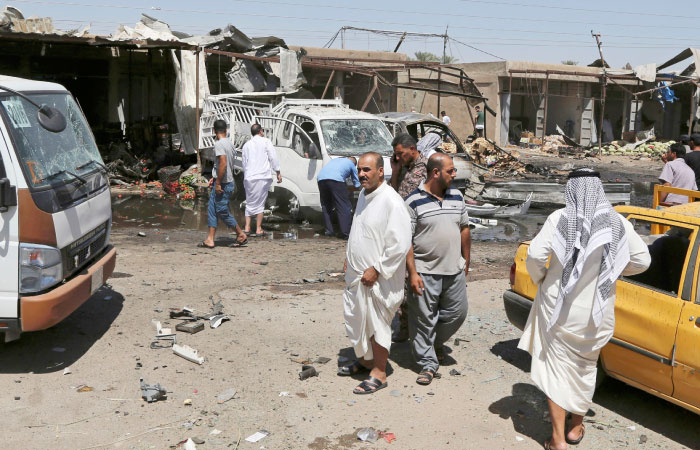 Civilians gather at the scene of a suicide car bombing at an outdoor market northeast of Baghdad on Tuesday. — AP