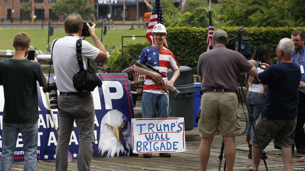 A supporter of Republican presidential candidate Donald Trump poses with a rifle while waiting for a pro Trump rally to begin near the Republican National Convention in Cleveland Ohio