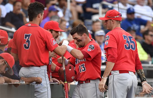 Arizona's Cody Ramer is congratulated after scoring on a Ryan Aguilar single against Coastal Carolina in the first inning of Game 1 of the NCAA Men's College World Series finals baseball game in Omaha Neb. Monday