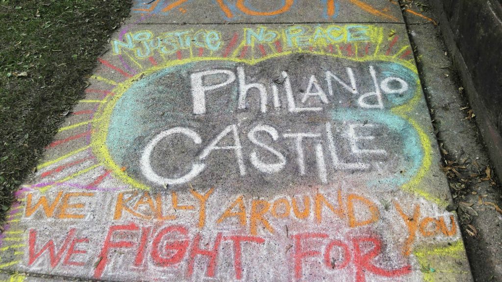 A chalk tribute to Philando Castile marked a sidewalk across the street from the Minnesota governor's residence as demonstrators gathered outside the residence Friday