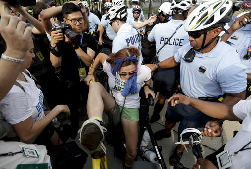 A demonstrator is taken into custody by police after climbing over a barricade near the AT&T Station Monday