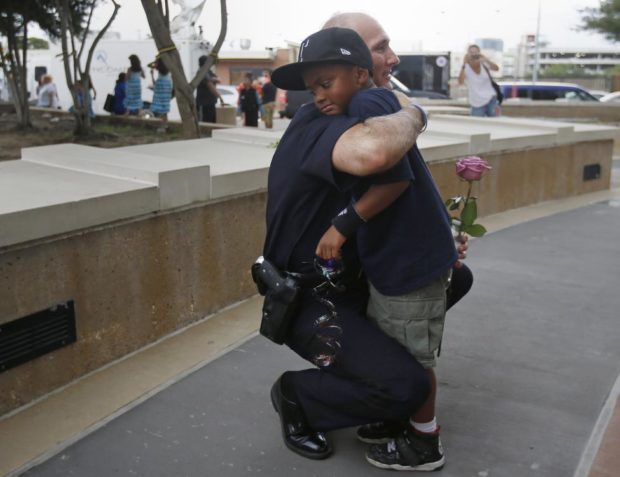 A Dallas Police officer hugs a child who came to pay respects at a makeshift memorial at Dallas Police Headquarters following the multiple police shootings in Dallas Reuters