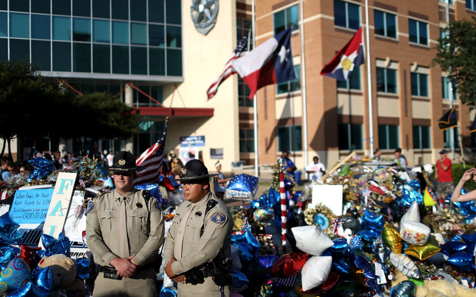 DALLAS TX- JULY 13 Police officers stand next to a growing memorial of flowers and balloons in front of the Dallas Police department headquarters