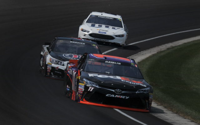 Denny Hamlin races with Kevin Harvick and Brad Keselowski at the Brickyard