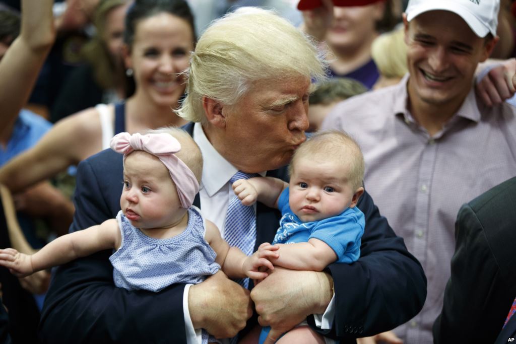 Republican presidential candidate Donald Trump kisses Kellen Campbell of Denver while also holding Evelyn Keane of Castle Rock Colo. during a campaign rally in Colorado Springs Colo