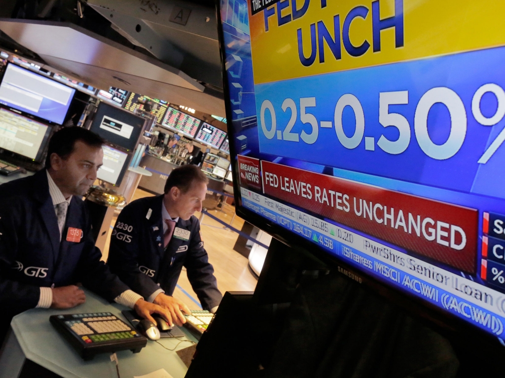 Dilip Patel left and Glenn Carell work at a post on the floor of New York Stock Exchange minutes after the announcement that interest rates will stay where they are