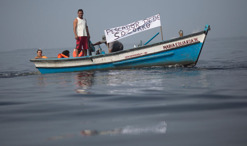 Fishermen protest contamination in Guanabara Bay on July 3 “Pescador pede socorro” means “fishermen ask for help.” Image via AP