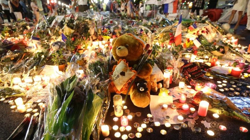 A teddy bear is laid with flowers and candles to honor the victims of an attack on the Promenade des Anglais near the area where a truck mowed through revelers in Nice southern France Saturday