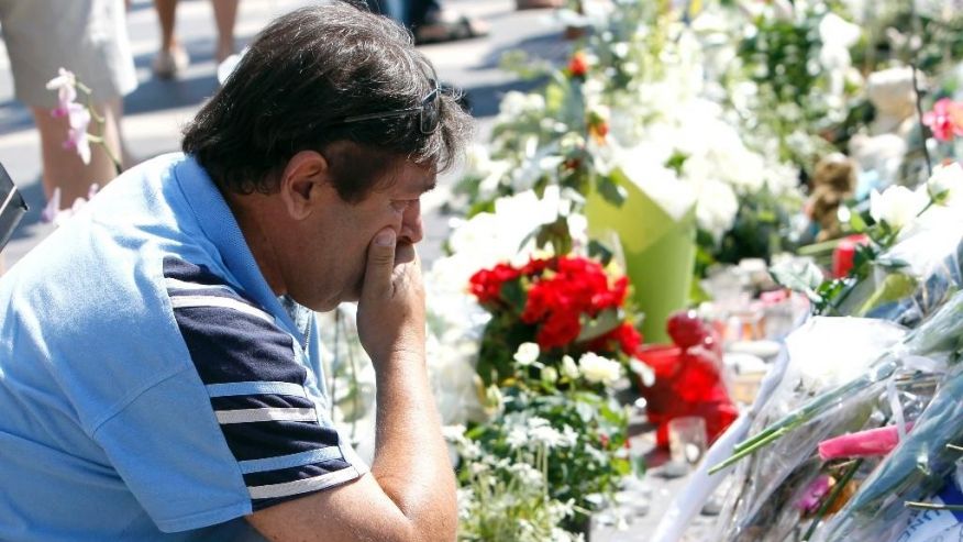 A man reacts as he looks flowers placed at a new memorial in a gazebo in a seaside park of the Promenade des Anglais in Nice southern France Tuesday