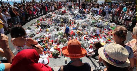 A teddy bear is laid with flowers and candles to honor the victims of an attack on the Promenade des Anglais near the area where a truck mowed through revelers in Nice southern France Saturday