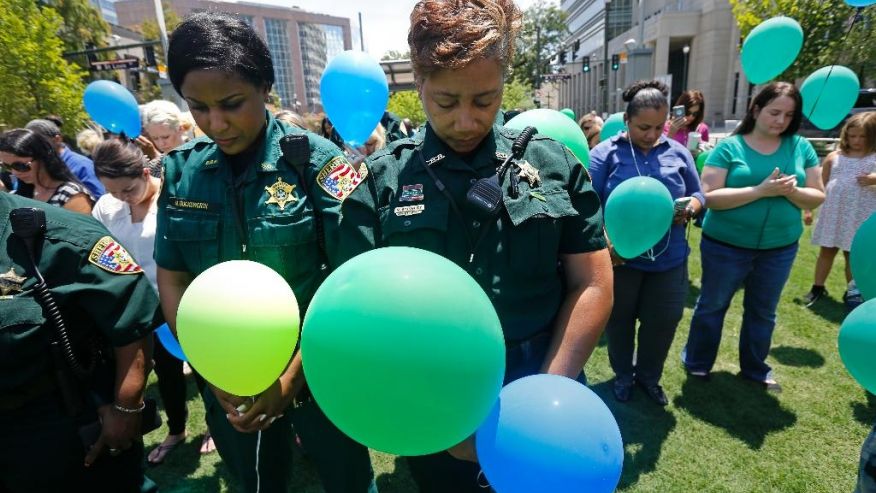 East Baton Rouge Sheriff's deputies Natasha Stingley right and Minnie Ducksworth left bow their heads in prayer before releasing balloons at a noon vigil organized by municipal court workers in downtown Baton Rouge La. Wednesday