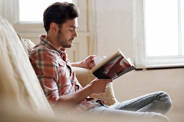 Man sitting on sofa reading a book