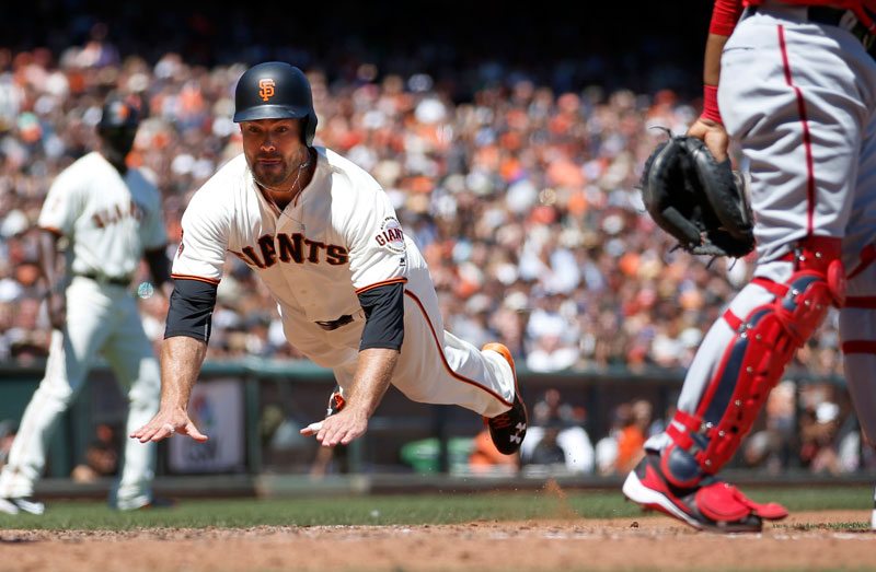 Mac Williamson dives toward home plate to score against the Washington Nationals on Saturday