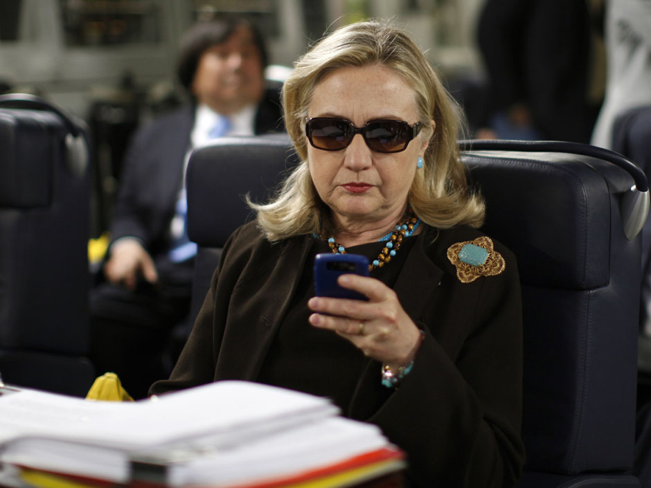 Then-Secretary of State Hillary Clinton checks her Blackberry from a desk inside a C-17 military plane in 2011