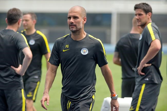 Manchester City manager Pep Guardiola center leaves the field after his team's training session at the Olympic Sports Center Stadium in Beijing Sunday