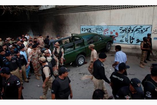 Pakistan army soldiers and police officers gather next to a damaged army vehicle after an attack in Karachi Pakistan Tuesday