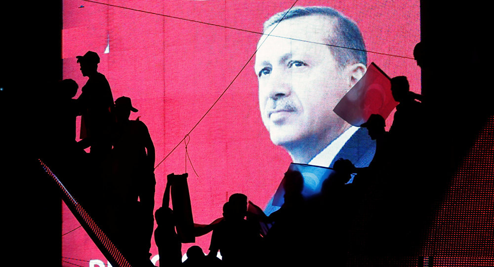 Turkish Supporters are silhouetted against a screan showing President Tayyip Erdogan during a pro-government demonstration in Ankara Turkey