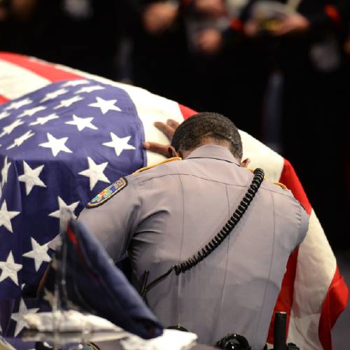 Baton Rouge police Cpl. Montrell Jackson's unit kneels and touches his casket during his funeral service at the Living Faith Christian Center in Baton Rouge La. Monday