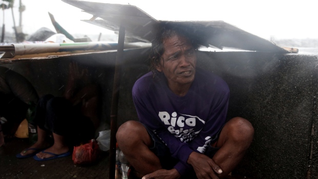 Fishermen take temporary shelter on a sidewalk due to bad weather brought by Typhoon Nepartak near Manila Bay Philippines