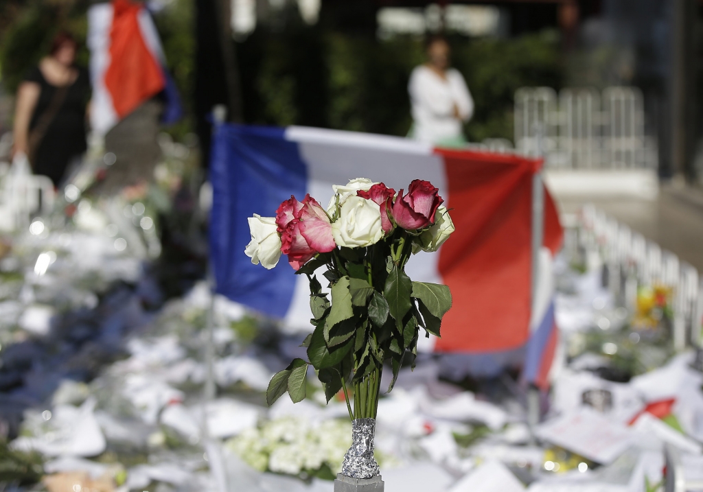 Floral and papers tributes are laid with a French flag near the scene of a truck attack in Nice southern France Saturday