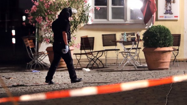 A special police officer examines the scene after an explosion in a public place in Ansbach Germany Monday. Bavaria's top security official says a man who blew himself up near an open-air music festival in the southern German city was a 27-year-old