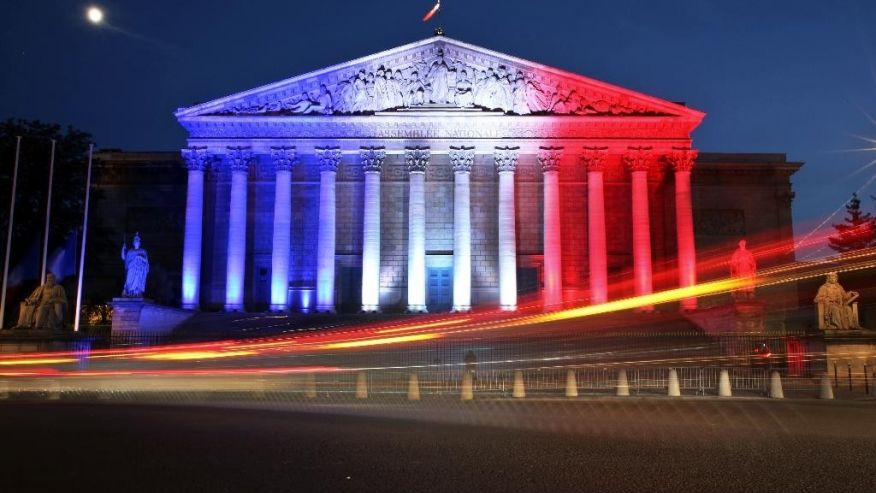 Cars pass by the National Assembly illuminated in the French national colors in honor of the victims of Thursday's attack in Nice south of France in Paris Friday