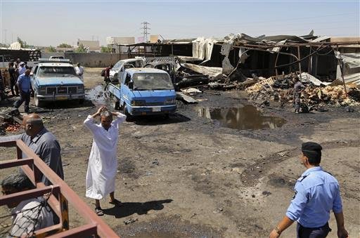 Civilians gather at the scene of a deadly suicide car bombing at an outdoor vegetable and fruit market in a Shiite-dominated district in northeastern Baghdad Iraq Tuesday