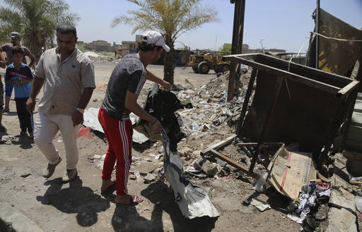 Civilians clean the scene of a suicide bombing at the northern neighborhood of Shula Baghdad Iraq Wednesday