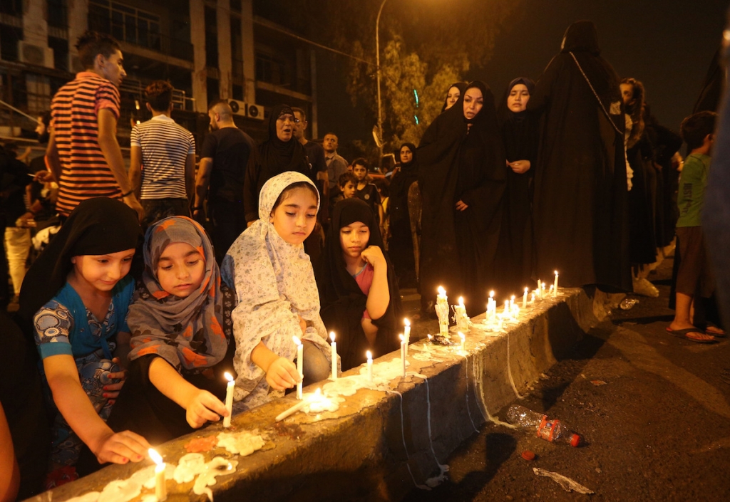 People light candles at the scene of a massive car bomb attack in Karada a busy shopping district where people were shopping for the upcoming Eid al Fitr holiday in the centre of Baghdad Iraq on Monday