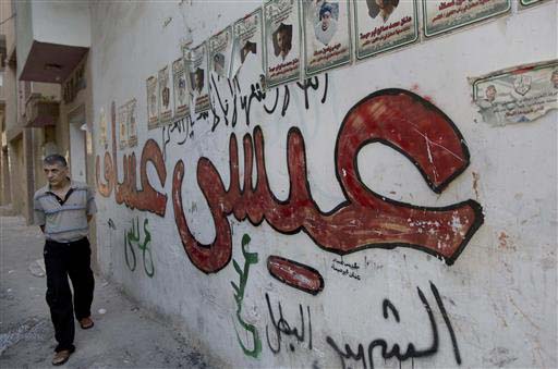 A Palestinian man walks past a graffiti with Arabic that reads'Issa Assaf the Martyr hero' on a wall near Assaf's house that was demolished by the Israeli army in the West Bank refugee camp of Qalandia at the outskirts of Ramallah Monday