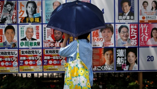 A voter looks at election campaign posters for Japan