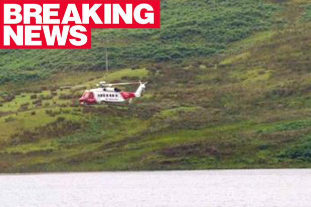 A rescue helicopter flies over Loch nan Druimnean