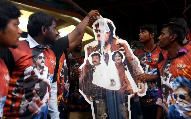 Fans pour milk on a cutout of actor Rajinikanth outside a temple on the eve of the release of Tamil film