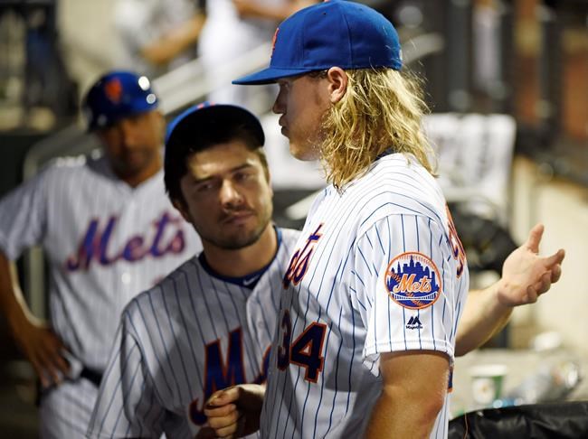 New York Mets catcher Travis d'Arnaud center talks with starting pitcher Noah Syndergaard in the dugout after he was taken out of the game by manager Terry Collins in the fifth inning of a baseball game Friday