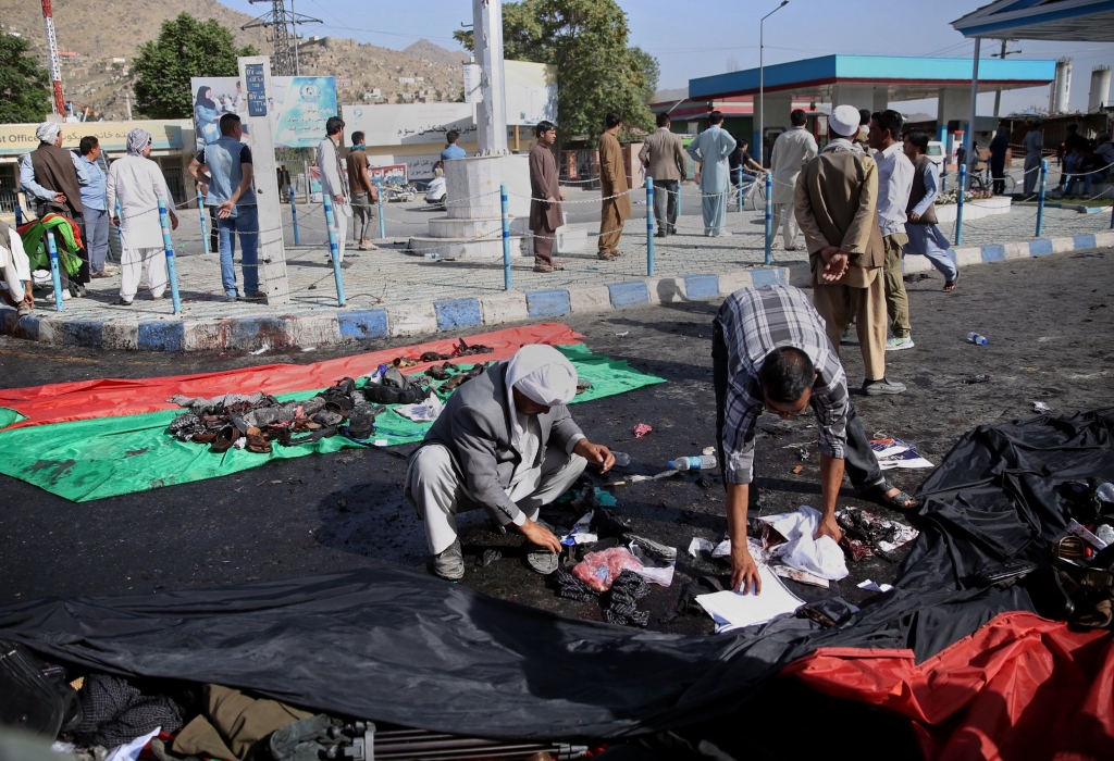 Afghans place property left behind by victims of an explosion that struck a protest march on a large representation of the Afghan flag in Kabul Afghanistan Saturday