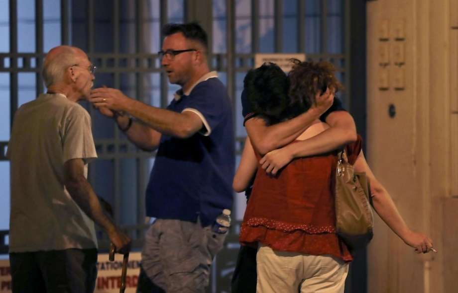 People react in the French Riviera town of Nice after a truck drives into a holiday crowd watching a fireworks display on Bastille Day. The incident that killed dozens of people is being called an “attack