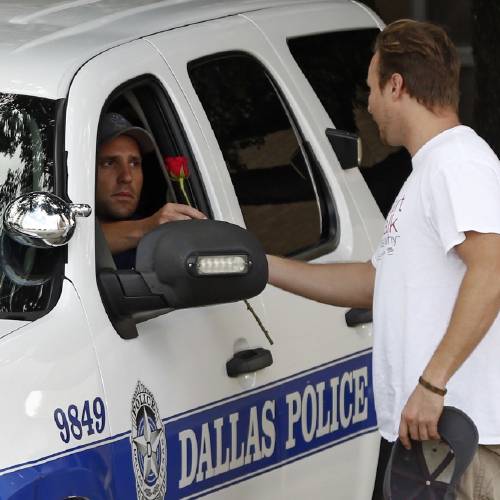 John Fife hands a police officer guarding Jack Evans Police Headquarters a rose in Dallas. Snipers opened fire on police officers in the heart of Dallas during protests over two recent fatal police