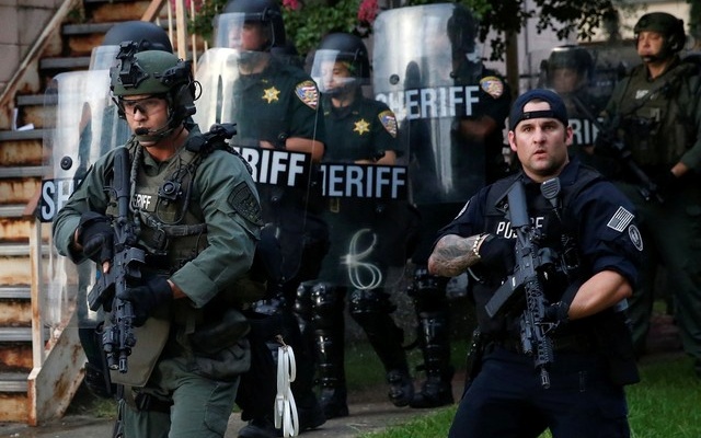 Law officers march down a street during protests in Baton Rouge Louisiana US