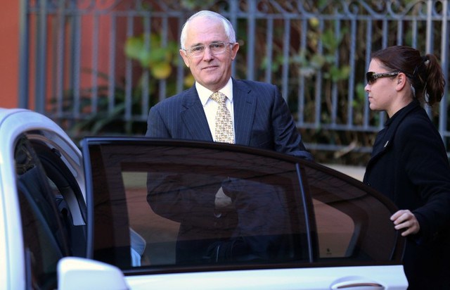 A security official assists Australian Prime Minister Malcolm Turnbull get into a car outside his home in Sydney Australia