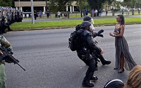 A protester is grabbed by police officers in riot gear after she refused to leave the motor way in front of the the Baton Rouge Police Department Headquarters in Baton Rouge La. Police made nearly 200 arres