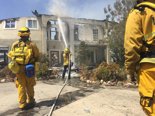 Authorities say 18 homes have been destroyed and an additional 1,500 are threatened as crews battle a massive wildfire in