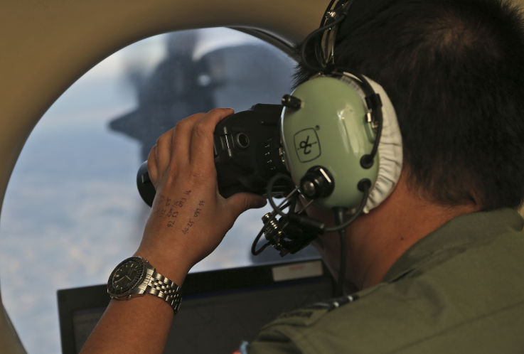 Flight Officer Jack Chen uses binoculars at an observers window on a Royal Australian Air Force P-3 Orion during the search for missing Malaysia Airlines Flight MH370 in Southern Indian Ocean Australia in March 2014. The hunt for Malaysia Airlines Fligh