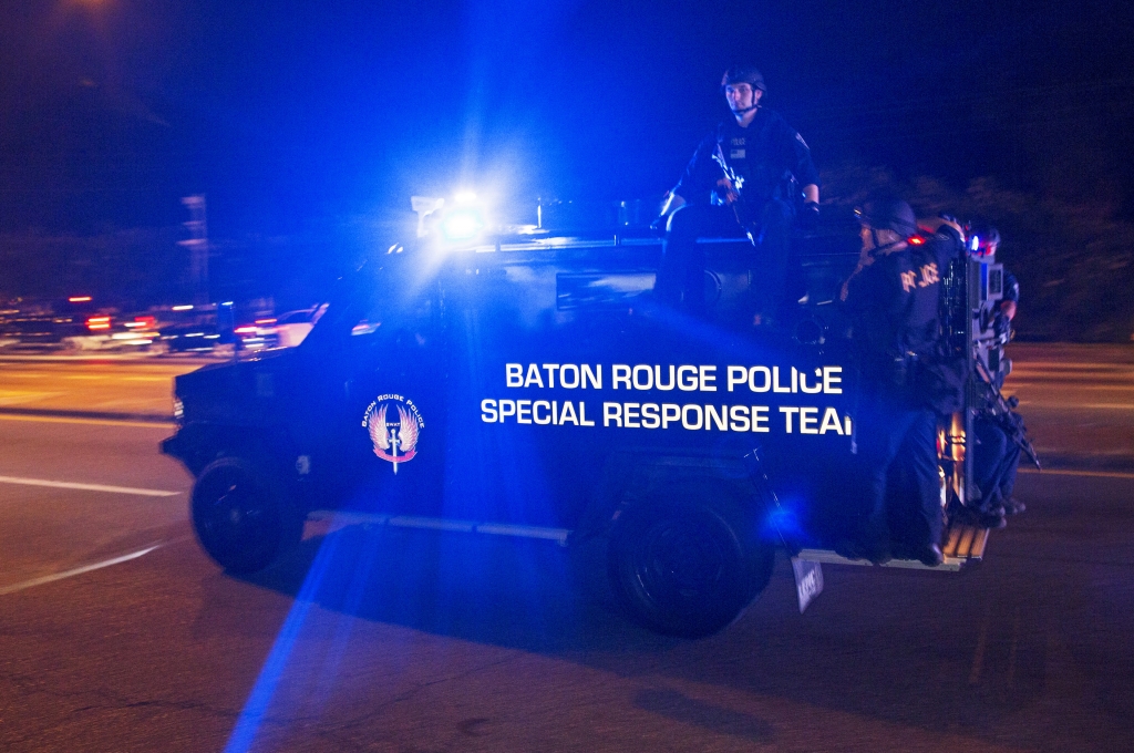 Sheriff deputies ride outside an armored vehicle in Baton Rouge La