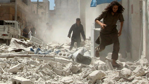 Men make their way through the rubble of damaged buildings at a site hit by airstrikes in Idlib Syria