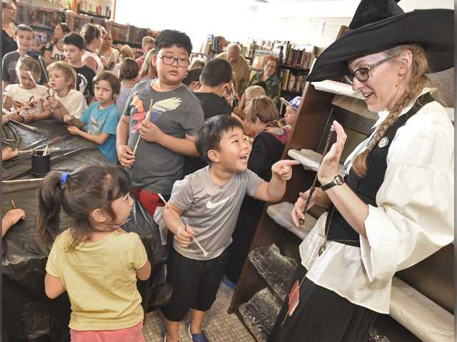 Liam Kim 6 center points to Diana Roach's magic wand as she get the dozens of children in attendance ready to paint their magic wands duirng the Harry Potter Birthday Celebration held at The Open Book store in Valencia on Saturday. Signal