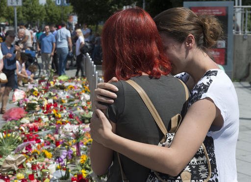 People mourn beside the Olympia shopping center where a shooting took place leaving nine people dead two days ago in Munich Germany Sunday