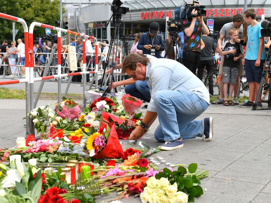 A man puts down flowers near a mall where a shooting took place leaving nine people dead the day before on Saturday